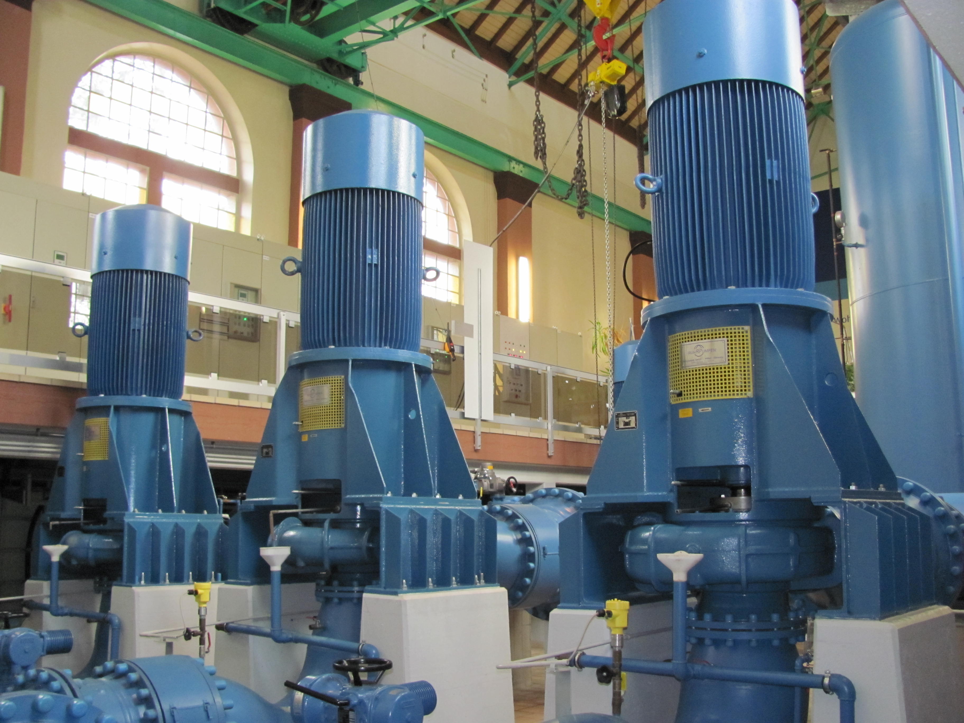 Es sind drei Kreiselpumpen in einer großen Halle des Wasserwerkes zu sehen.