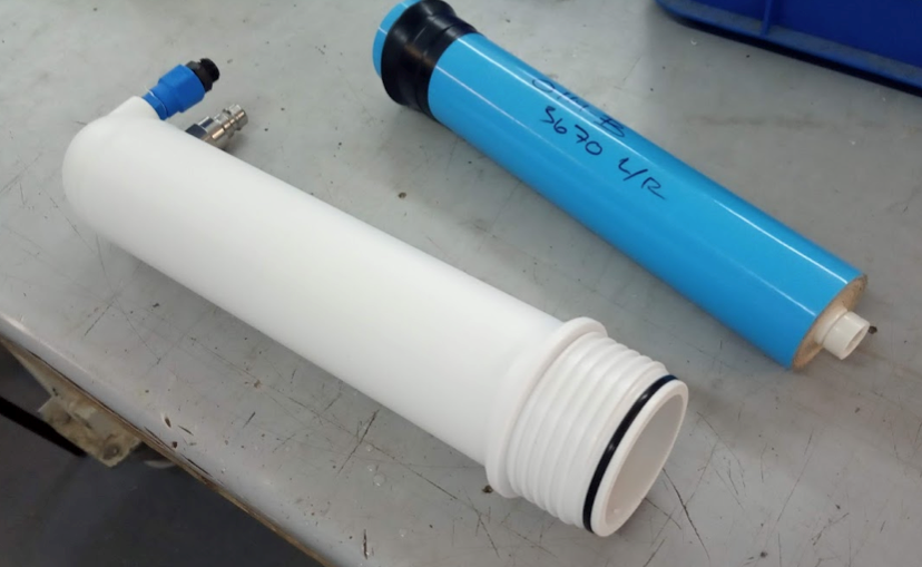 Seen in the figure is a cylindrical water filtration module, spiral wound, approx 30 cm long and 5 cm in diameter. Next to it is the pressure housing, with an open end, which implies that the module can be inserted into the housing for operation. 
